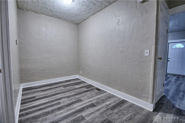 empty room with dark wood-type flooring and a textured ceiling