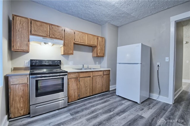 kitchen featuring sink, stainless steel electric range oven, a textured ceiling, dark hardwood / wood-style flooring, and white fridge