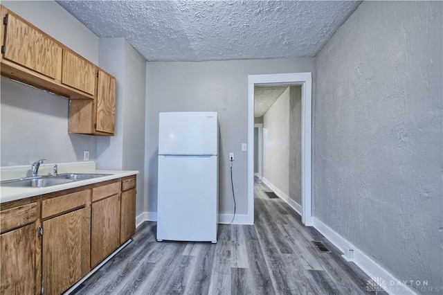 kitchen with sink, dark hardwood / wood-style floors, a textured ceiling, and white fridge