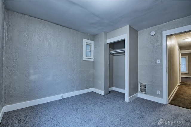 unfurnished bedroom featuring a closet and dark colored carpet