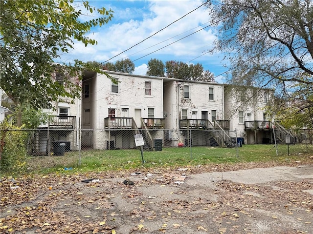 back of property with a wooden deck and a lawn