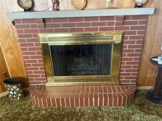 interior details with wooden walls, a fireplace, and carpet floors