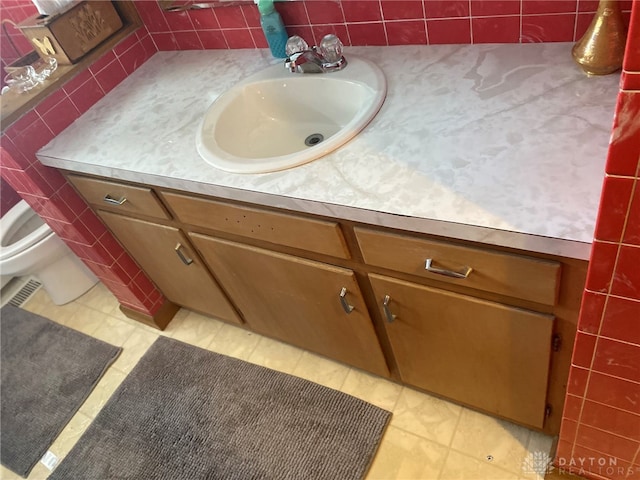 bathroom with toilet, vanity, tasteful backsplash, and tile patterned floors