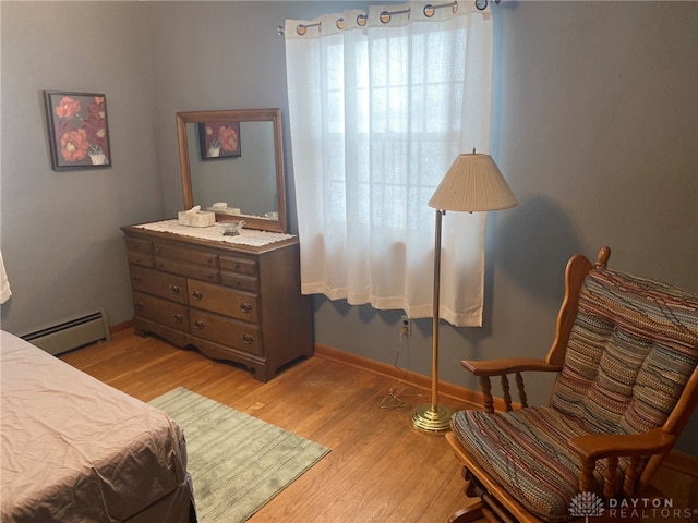 bedroom with a baseboard radiator and light hardwood / wood-style floors