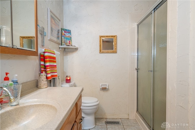 bathroom featuring tile patterned flooring, vanity, a shower with shower door, and toilet