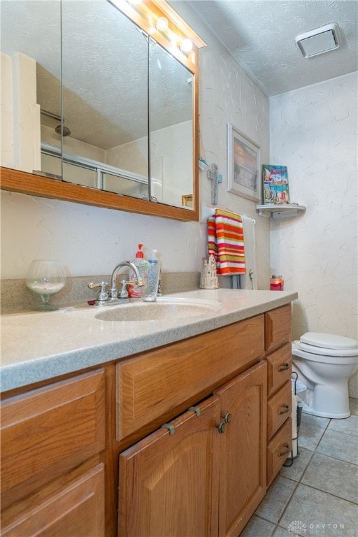 bathroom featuring vanity, a textured ceiling, toilet, and tile patterned flooring