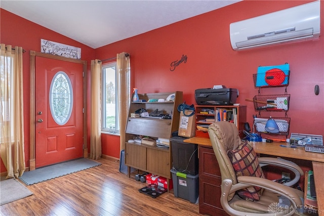 office space with a wall mounted air conditioner, light wood-type flooring, and lofted ceiling