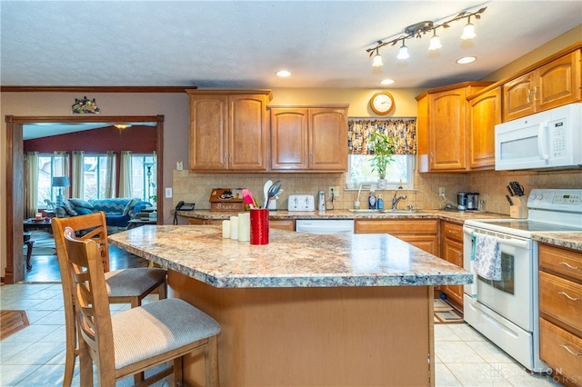 kitchen with a kitchen bar, tasteful backsplash, white appliances, a center island, and light tile patterned flooring