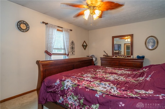 bedroom featuring ceiling fan, light colored carpet, and a textured ceiling