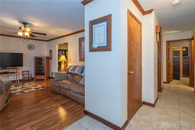 living room with ceiling fan, light hardwood / wood-style floors, a textured ceiling, and ornamental molding