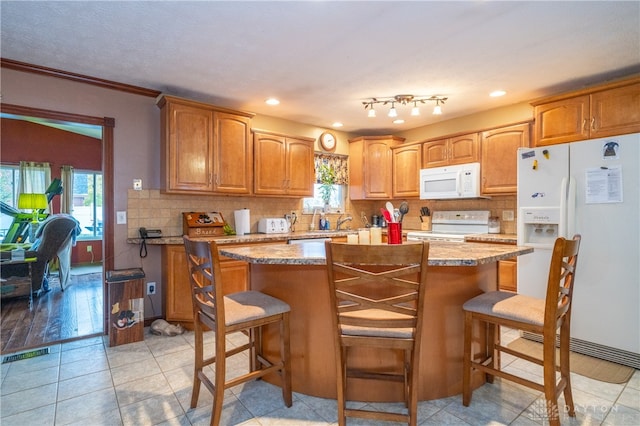 kitchen with a kitchen bar, decorative backsplash, a kitchen island, and white appliances