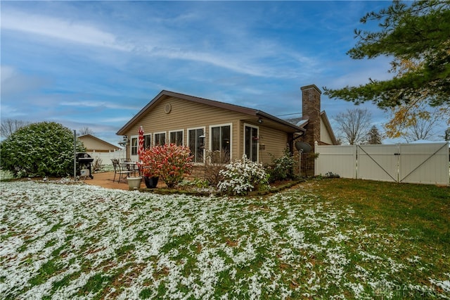 snow covered back of property with a yard and a patio