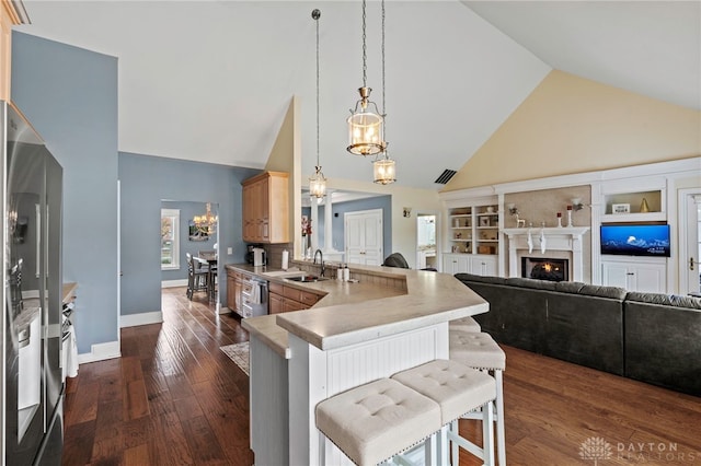 kitchen featuring kitchen peninsula, a breakfast bar, sink, light brown cabinets, and high vaulted ceiling