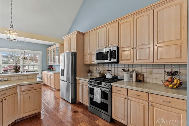 kitchen featuring pendant lighting, stainless steel appliances, lofted ceiling, and light brown cabinets