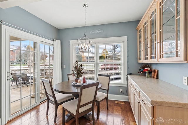 dining room with dark hardwood / wood-style flooring, plenty of natural light, and a notable chandelier