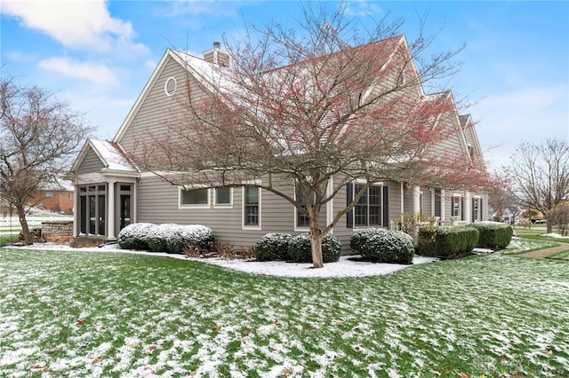 snow covered property with a yard and a sunroom