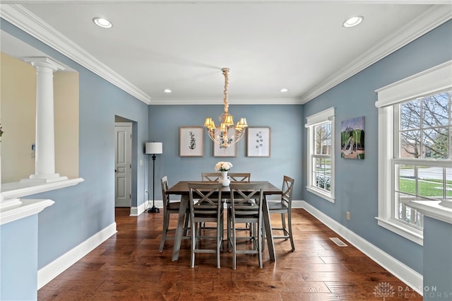 dining area with dark hardwood / wood-style flooring, ornate columns, ornamental molding, and a notable chandelier