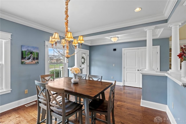 dining space with dark hardwood / wood-style floors, crown molding, a notable chandelier, and ornate columns