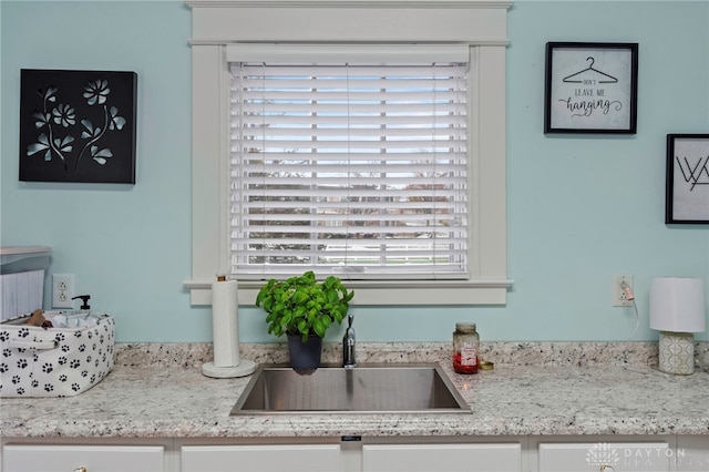 details featuring white cabinetry, light stone counters, and sink