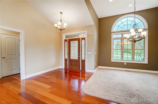 foyer with hardwood / wood-style floors, lofted ceiling, and an inviting chandelier