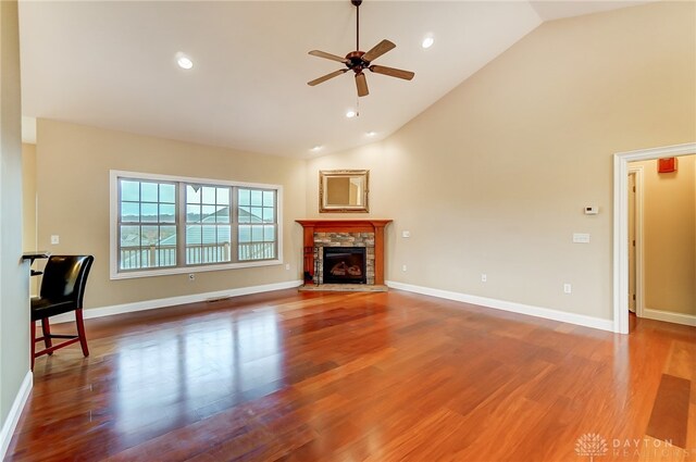 unfurnished living room featuring a fireplace, wood-type flooring, high vaulted ceiling, and ceiling fan