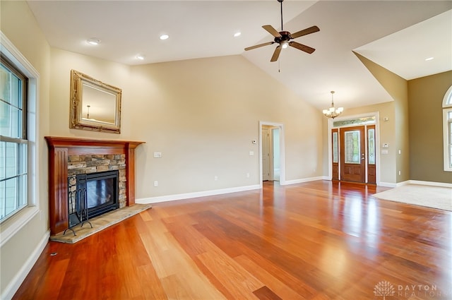 unfurnished living room featuring hardwood / wood-style flooring, ceiling fan with notable chandelier, a fireplace, and high vaulted ceiling