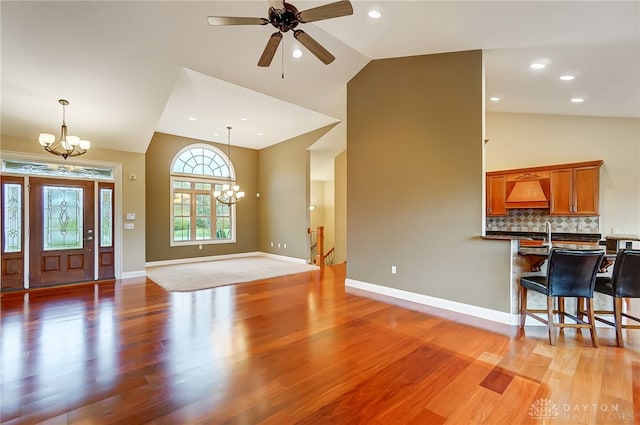 foyer featuring high vaulted ceiling, ceiling fan with notable chandelier, and hardwood / wood-style flooring