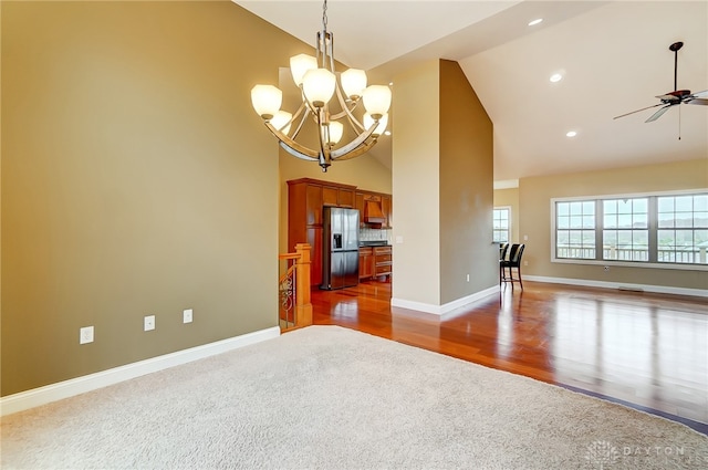 unfurnished living room featuring ceiling fan with notable chandelier, dark hardwood / wood-style flooring, and high vaulted ceiling