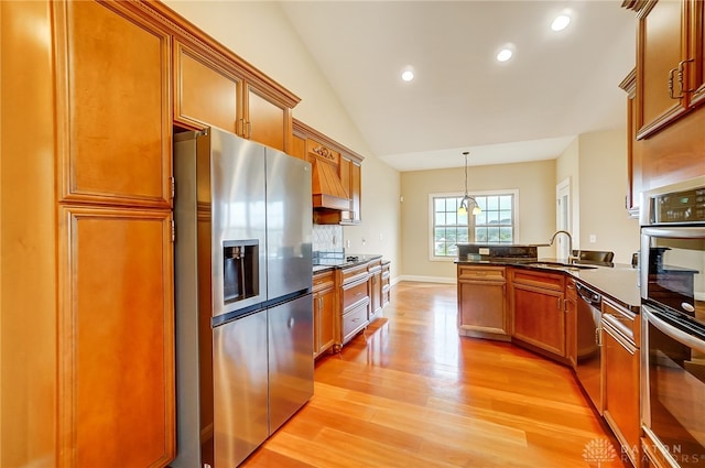 kitchen with sink, stainless steel appliances, pendant lighting, lofted ceiling, and light wood-type flooring