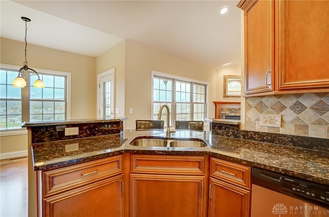 kitchen featuring stainless steel dishwasher, plenty of natural light, sink, and an inviting chandelier