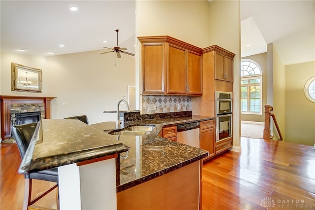 kitchen with ceiling fan, sink, stainless steel appliances, light hardwood / wood-style flooring, and decorative backsplash