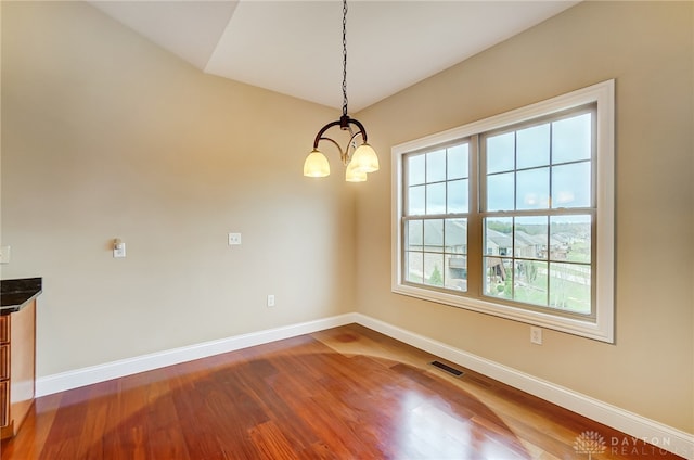 unfurnished dining area with hardwood / wood-style flooring and a chandelier