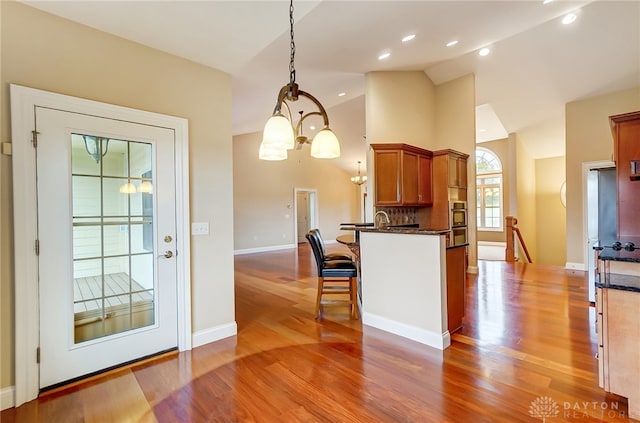 kitchen featuring a chandelier, pendant lighting, lofted ceiling, and wood-type flooring