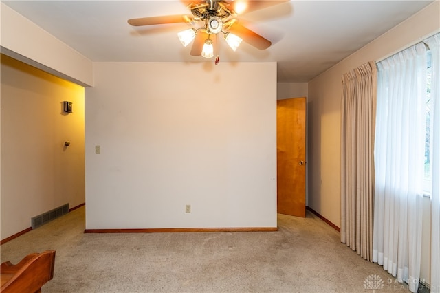 spare room featuring ceiling fan, light carpet, and a wealth of natural light