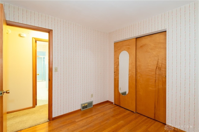 unfurnished bedroom with wood-type flooring and a closet