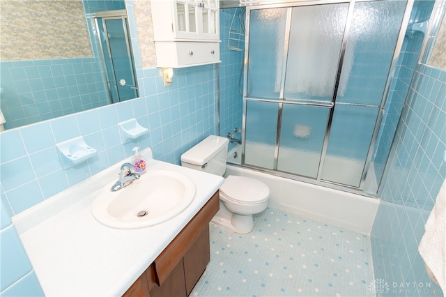 full bathroom featuring vanity, enclosed tub / shower combo, tile walls, and toilet