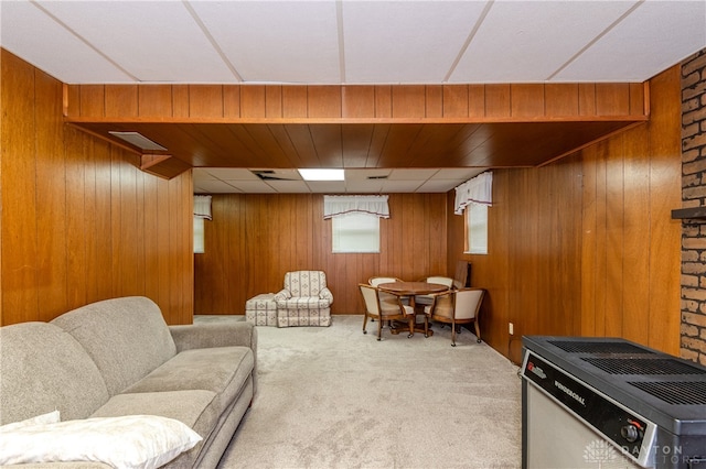 carpeted living room with heating unit and wood walls