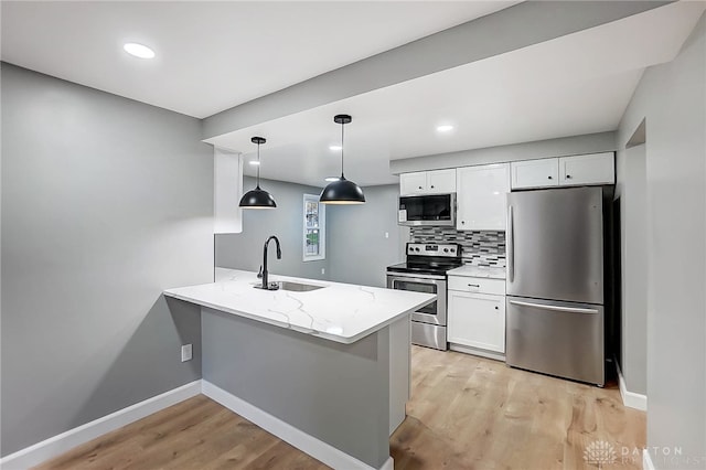 kitchen featuring white cabinetry, sink, stainless steel appliances, kitchen peninsula, and decorative light fixtures