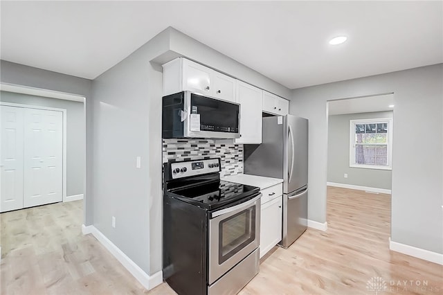 kitchen featuring decorative backsplash, white cabinetry, stainless steel appliances, and light hardwood / wood-style floors