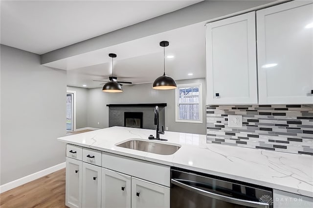 kitchen featuring light stone countertops, sink, white cabinets, and stainless steel dishwasher