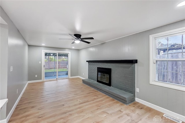 unfurnished living room featuring ceiling fan, light hardwood / wood-style floors, and a brick fireplace