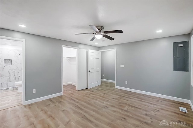 unfurnished bedroom featuring ensuite bath, ceiling fan, a spacious closet, light hardwood / wood-style flooring, and electric panel