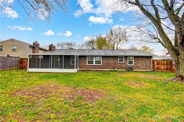 rear view of house with a sunroom and a lawn