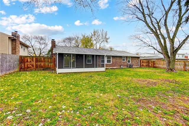 rear view of house featuring a sunroom and a yard