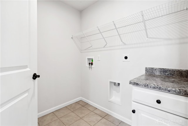 clothes washing area featuring hookup for an electric dryer, washer hookup, light tile patterned floors, and cabinets