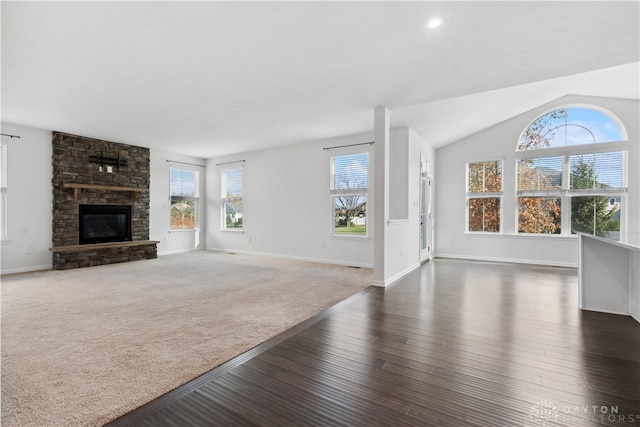 unfurnished living room with a fireplace, dark wood-type flooring, plenty of natural light, and lofted ceiling