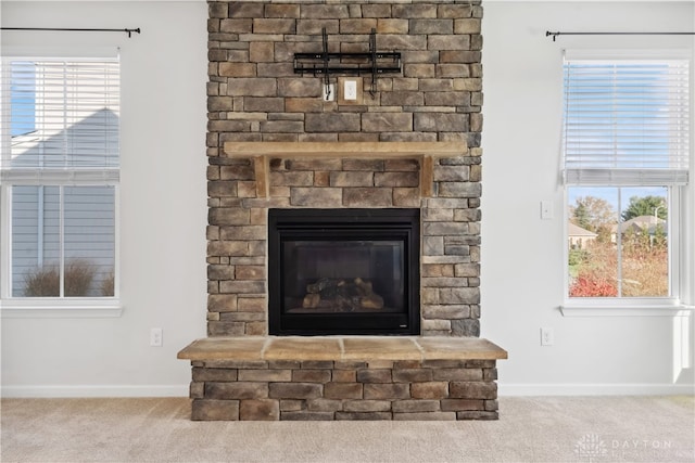 interior details featuring a stone fireplace and carpet floors