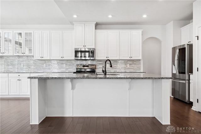 kitchen featuring appliances with stainless steel finishes, dark stone counters, sink, white cabinets, and dark hardwood / wood-style floors