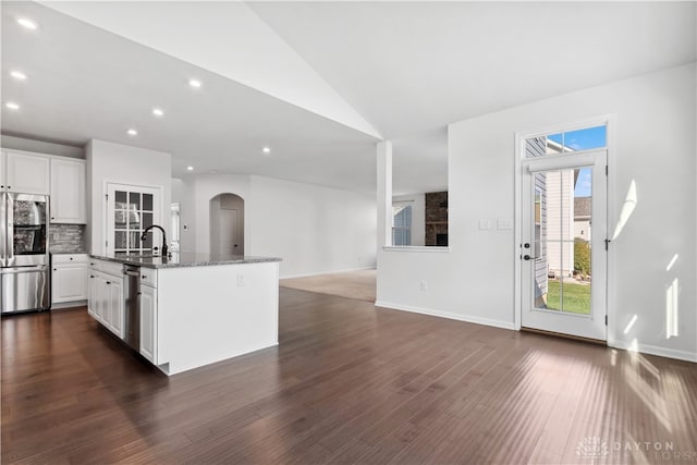 kitchen featuring dark wood-type flooring, an island with sink, lofted ceiling, white cabinets, and appliances with stainless steel finishes