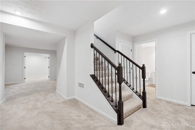 staircase featuring carpet